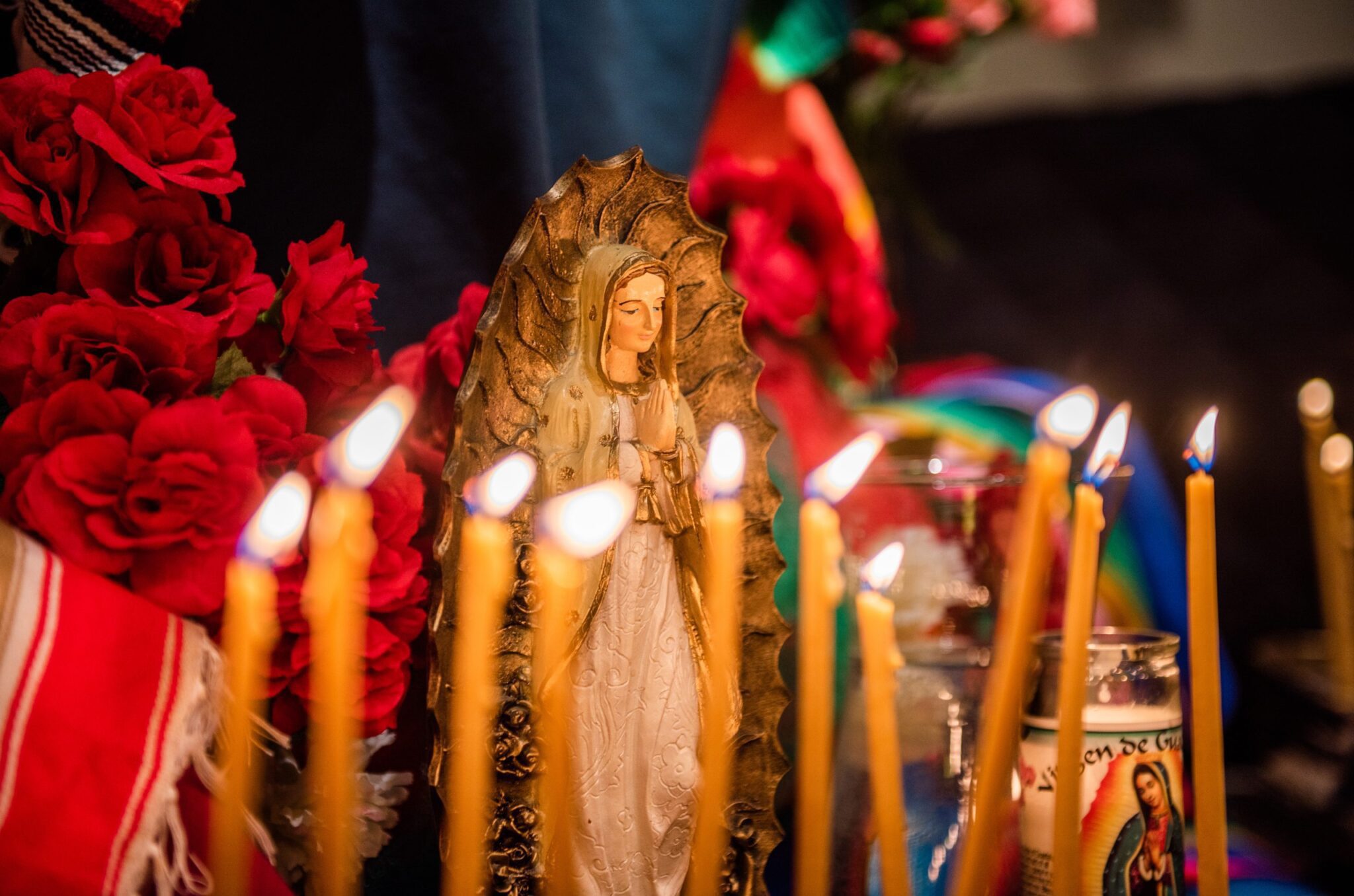 Small statue figures of the Virgin Mary and candles are lit at a church altar